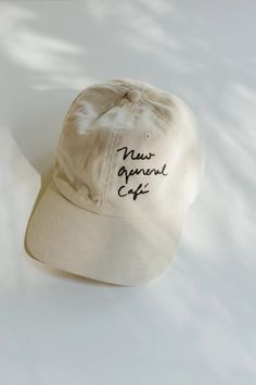 a cap with the words new arrival cafe written on it sitting on a white surface