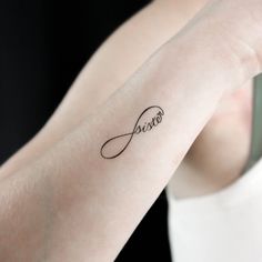 a woman's wrist tattoo with the word jesus written in cursive font