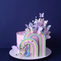 there is a pink cake with butterflies and rainbows on it that has been decorated