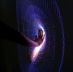 a person's hand touching the center of a circular object with purple and blue lights