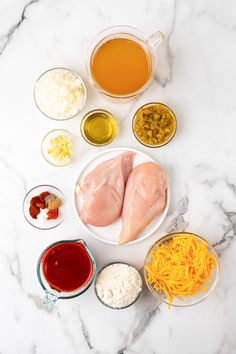 ingredients to make chicken broth laid out on a marble countertop with bowls and sauces