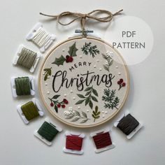 a cross stitch christmas ornament surrounded by spools of thread and needles