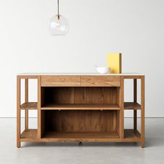 a wooden shelf with a light hanging from it's side and a bowl on top