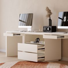 an office desk with two computer monitors and a clock on the wall next to it