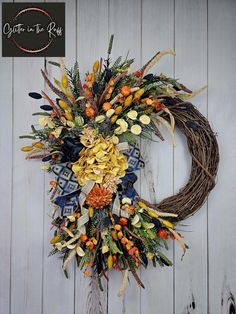 a wreath is hanging on the wall next to a wooden door with an orange and yellow flower arrangement