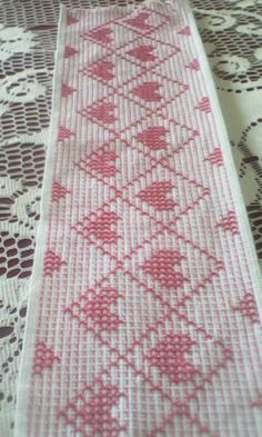 a pink and white table runner sitting on top of a doily