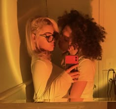 two women taking a selfie in front of a mirror with the reflection of them