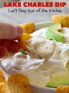 a person dipping some chips into a white bowl with guacamole and avocado