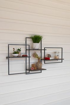 three shelves on the side of a white house with plants and other things in them