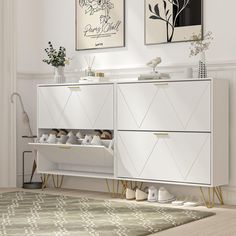 a white cabinet with two pictures above it and shoes on the bottom shelf in front of it