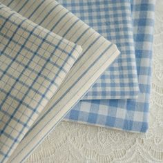 three pieces of blue and white checkered fabric on top of eachother's tablecloth