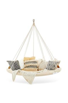 a hanging chair with pillows and blankets on it's back, in front of a white background