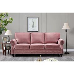 a living room with a pink couch and two lamps on the side tables in front of it