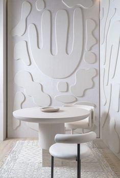 a white table and chairs in front of a wall with abstract art on it's walls