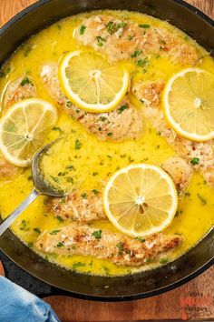 a pan filled with chicken and lemons on top of a wooden table