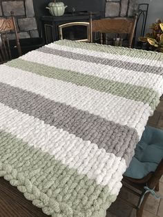 a table with a blanket on top of it in front of a fire place and chairs