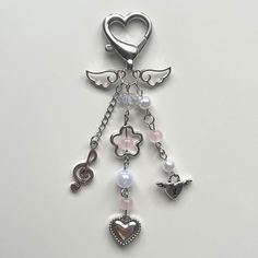 a keychain with charms attached to it on a white surface, including an angel's wing