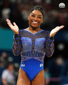 a woman in a blue leotard is smiling and holding her hands out