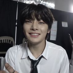 a young man wearing a white shirt and black tie with an umbrella in the background