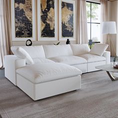 a living room with a white couch and two large paintings on the wall behind it