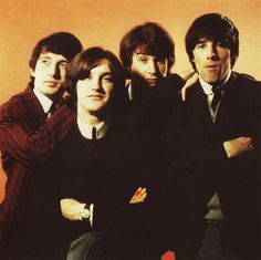 the beatles posing for a photo in front of an orange background