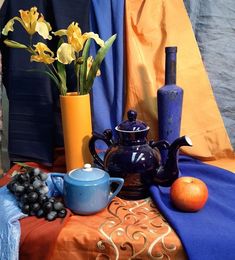 a table topped with vases filled with flowers next to an orange and blue cloth