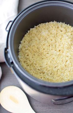 a pot filled with rice next to two wooden spoons