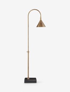 a brass colored lamp with a black base and a metal shade on the top, against a white background