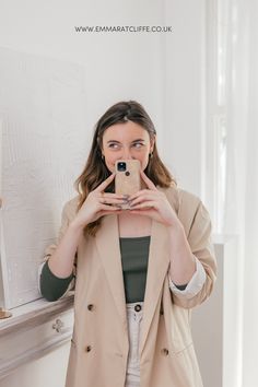 a woman taking a selfie in front of a mirror with her cell phone up to her face