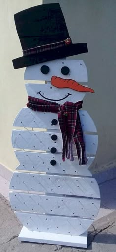 a snowman made out of white boards with a hat and scarf on it's head