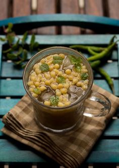 a glass cup filled with food sitting on top of a wooden table next to green beans