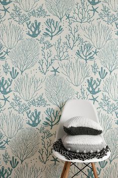 a white chair sitting in front of a wall with blue and green corals on it