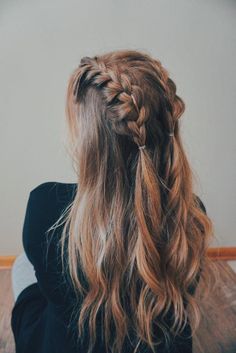 a woman with long hair is sitting on the floor and has her back to the camera