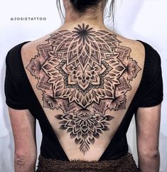 the back of a woman's neck with an intricate tattoo design