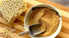 a bowl filled with noodles next to a wooden cutting board