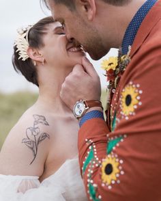 a man and woman standing next to each other with tattoos on their chests, looking at each other