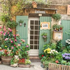 a garden with potted plants and flowers in front of a green door that says ruelle lave