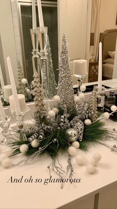 a white table topped with lots of candles and christmas tree decorations on top of it