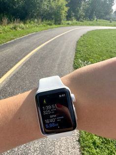 an apple watch on someone's arm with a road in the background