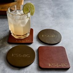 three coasters with names on them sitting next to a drink and a lime slice