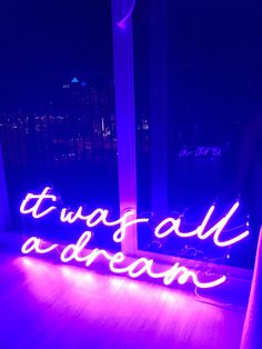 a neon sign that says it was all a dream on the floor in front of a window