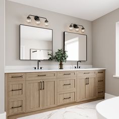 a bathroom with double sinks and two mirrors on the wall next to a bathtub