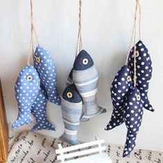 three blue and white fish hanging from strings next to a small wooden slatted bench