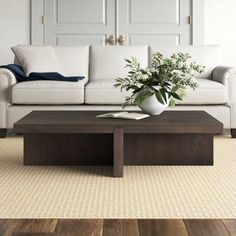 a white couch sitting next to a wooden table on top of a carpeted floor