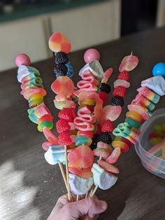 a hand holding a bunch of lollipops on top of a wooden table