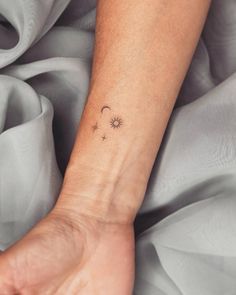 a woman's wrist with a small sun and moon tattoo on her left arm