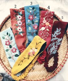 five different types of headbands with flowers on them in a wicker basket