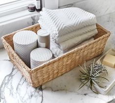 a wicker basket with towels and soaps on a marble countertop next to a window