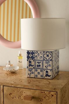 a blue and white lamp sitting on top of a wooden dresser next to a mirror