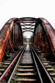 an old rusty bridge with train tracks going over it